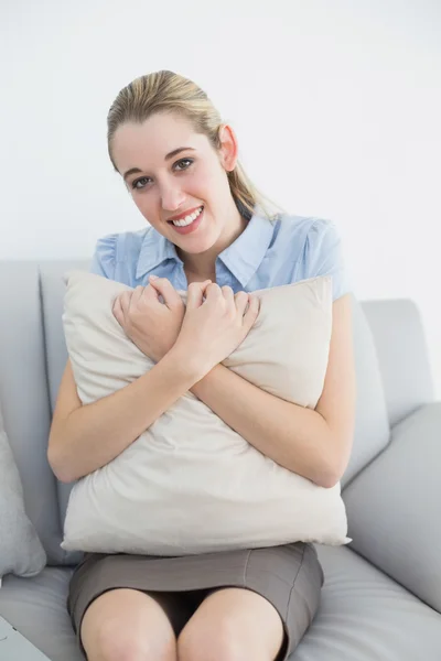 Cute chic businesswoman holding a pillow sitting on couch — Stock Photo, Image