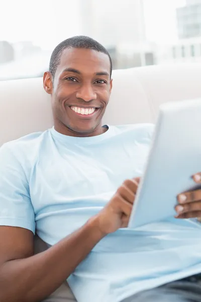 Casual άνδρα χαμογελώντας Αφρο χρησιμοποιώντας ψηφιακή δισκίο στον καναπέ — Φωτογραφία Αρχείου