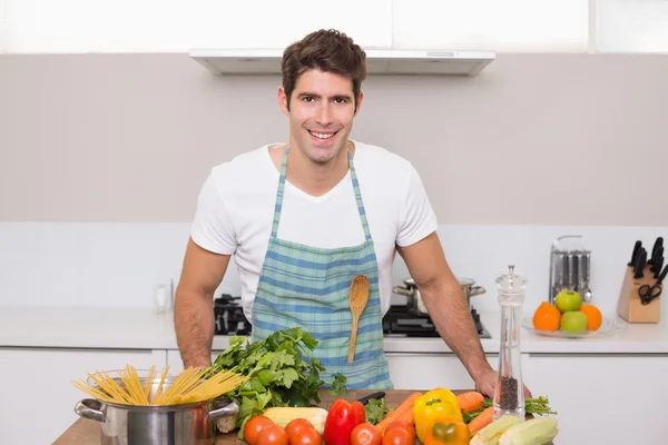 Jovem sorridente com legumes de pé na cozinha — Fotografia de Stock