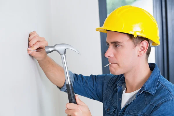Handyman hammering nail in wall — Stock Photo, Image
