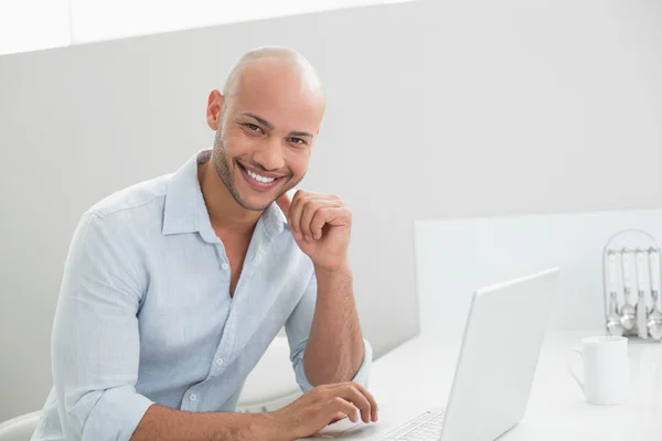 在家里使用的笔记本电脑的休闲男人微笑着 — 图库照片