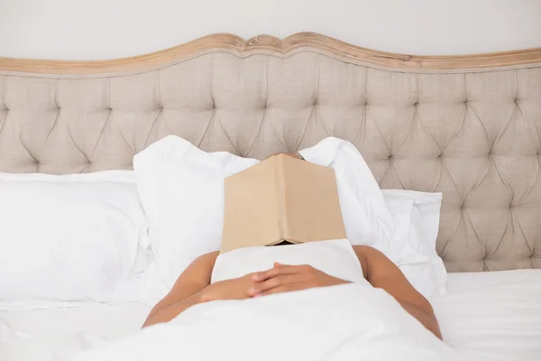 Relaxado homem com livro sobre rosto deitado na cama — Fotografia de Stock