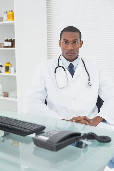 Serious male doctor sitting with computer at medical office — Stock Photo, Image