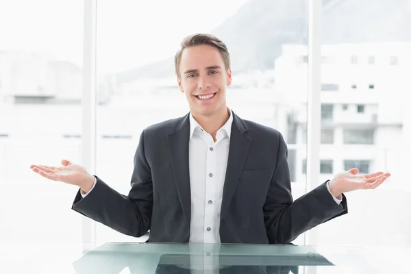 Smiling businessman with hand gesture at office desk — Stock Photo, Image