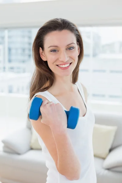 Fit woman exercising with dumbbell in fitness studio — Stock Photo, Image