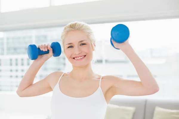 Mujer sonriente con mancuernas en el gimnasio — Foto de Stock