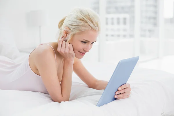 Contenido casual joven rubia usando tableta PC en la cama — Foto de Stock