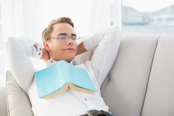 Relajado joven reflexivo con libro acostado en el sofá —  Fotos de Stock