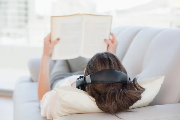 Mujer de cabello castaño disfrutando de la música mientras lee un libro —  Fotos de Stock