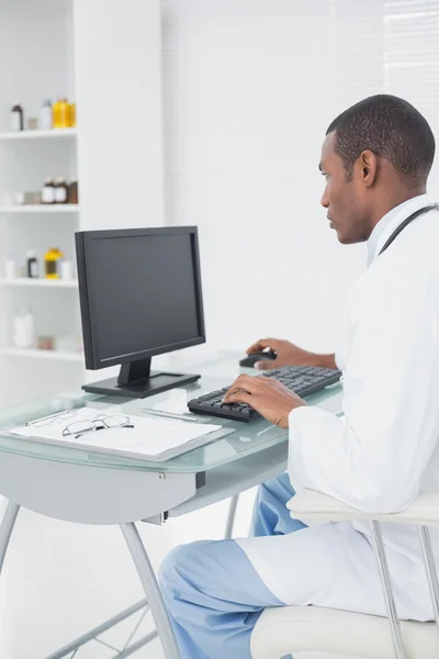 Médico concentrado usando computador em consultório médico — Fotografia de Stock