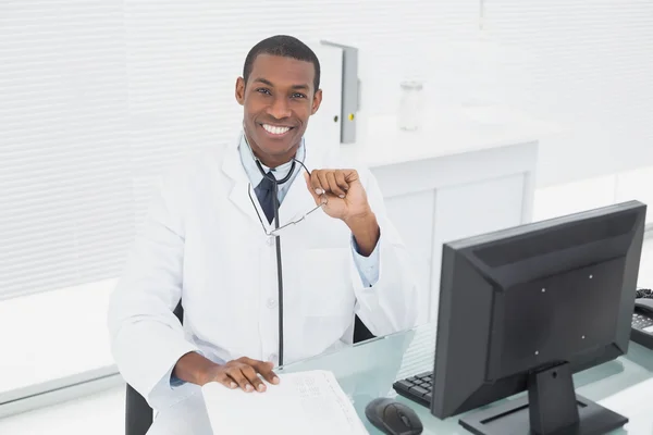 Smiling male doctor sitting with computer at medical office — Stock Photo, Image