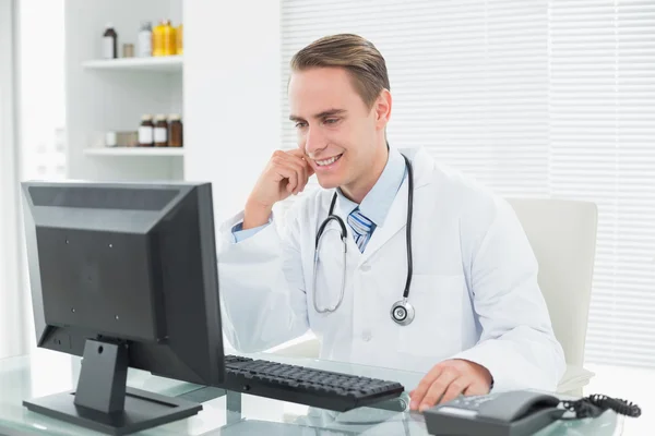 Jistý lékař sedí s počítačem v ordinaci Stock Fotografie