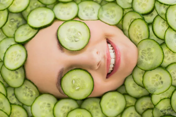 Mooie vrouw met gezichtsmasker van komkommer plakjes op gezicht Stockfoto