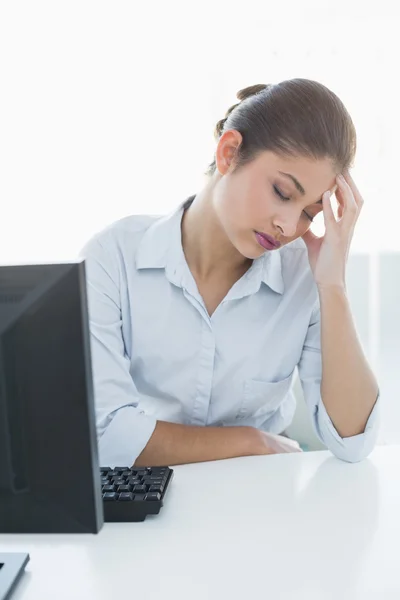 Businesswoman suffering from headache in front of laptop Stock Picture