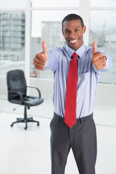 Elegante hombre de negocios afro señalando pulgares hacia arriba en la oficina Fotos De Stock
