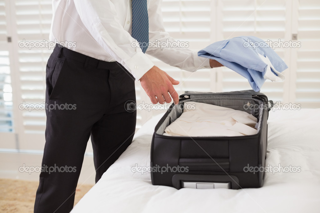 Mid section of businessman unpacking luggage at hotel