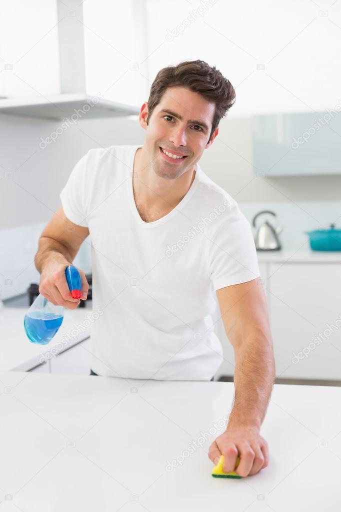 Smiling young man cleaning kitchen counter