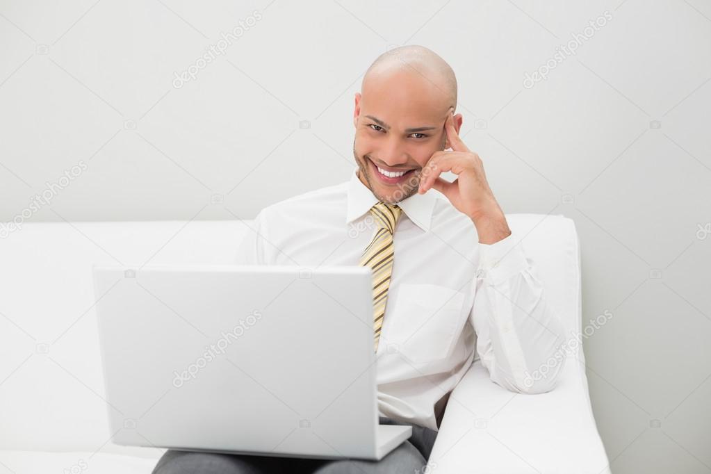 Elegant businessman using laptop on sofa at home