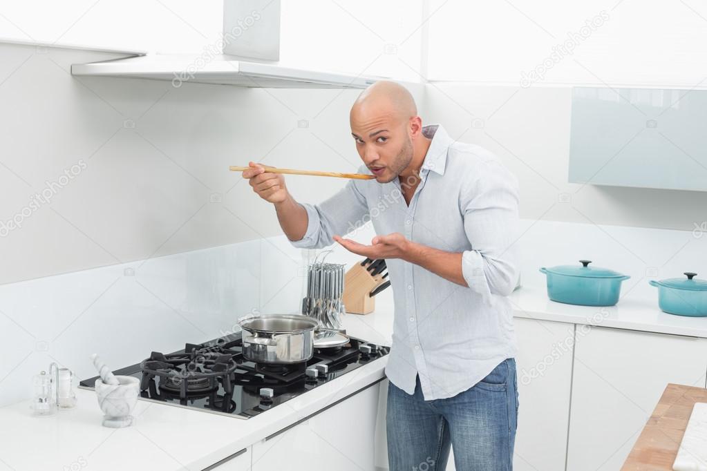 Man tasting food while preparing in kitchen