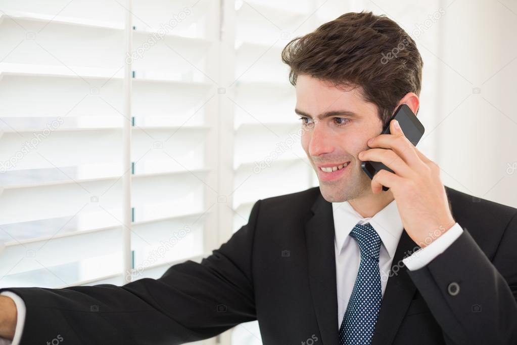 Smiling businessman using mobile phone while clenching fist