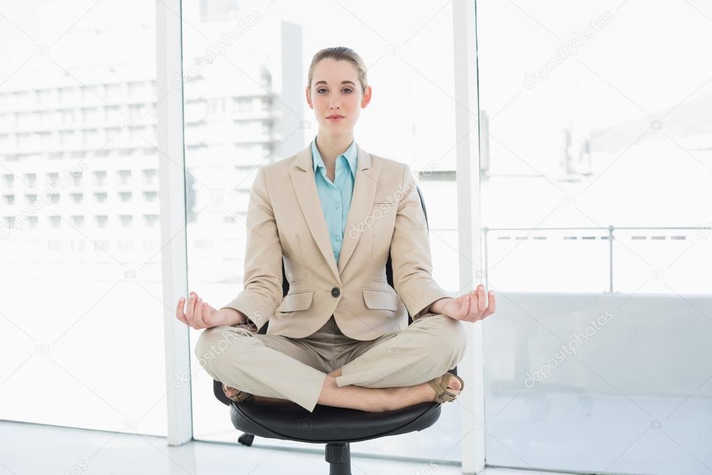 Beautiful calm woman sitting in lotus position on her swivel chair