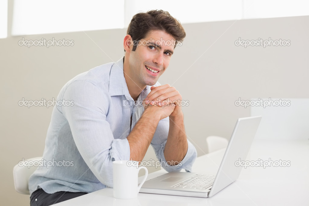 Casual smiling man using laptop at home
