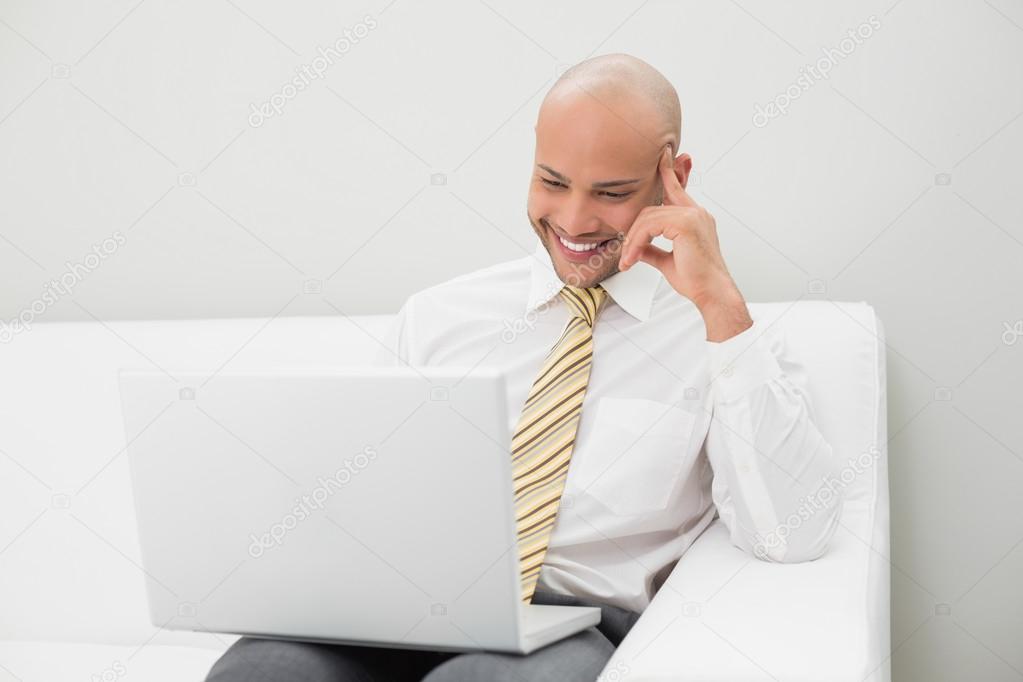 Elegant businessman using laptop on sofa at home