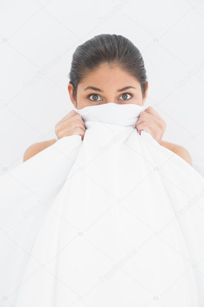 Portrait of a woman covering face with bedsheet