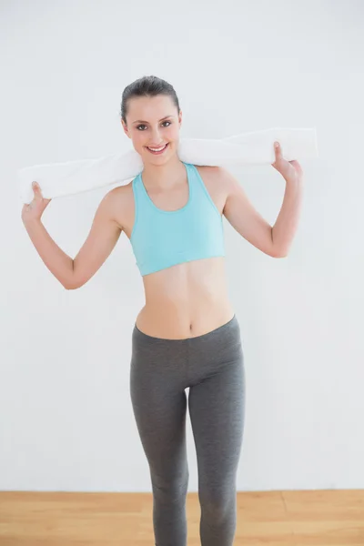 Fit young woman with towel around neck against wall — Stock Photo, Image