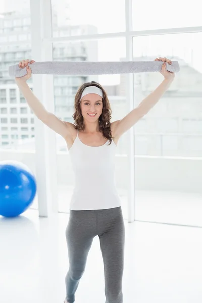 Fit young woman holding up towel in a fitness studio — Stock Photo, Image