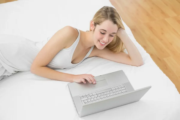 Krásná mladá žena pomocí její zápisník ležící na posteli — Stock fotografie
