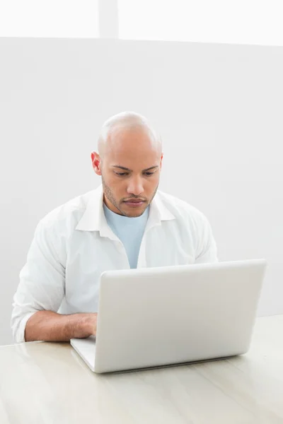 Casual ernstige jonge man met behulp van laptop aan balie — Stockfoto