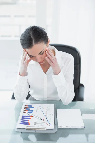 Worried businesswoman with graphs at office desk — Stock Photo, Image