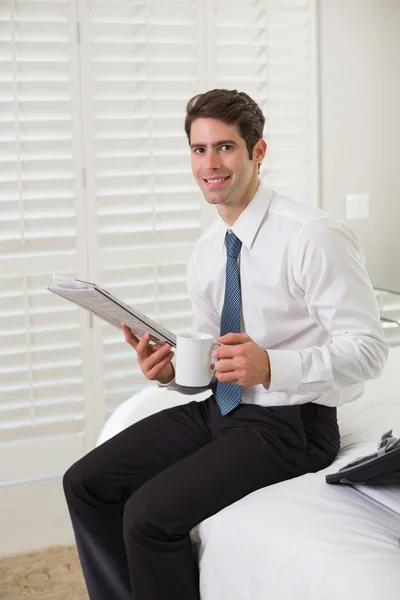 Empresario con taza de café y periódico en una habitación de hotel —  Fotos de Stock