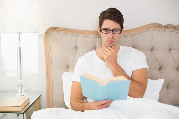 Rilassato giovane uomo lettura libro a letto — Foto Stock