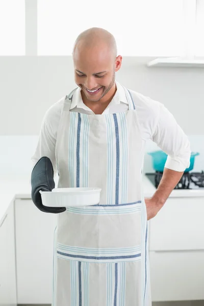 Homme souriant tenant un plat de cuisson dans la cuisine — Photo