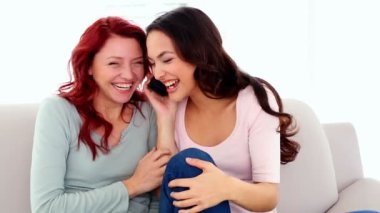telefon ederek kanepede oturan smartphone ile heyecanlı mutlu güzel kadınlar