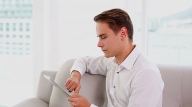 ciddi genç adam kanepede oturan onun tablet kullanma