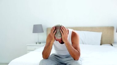 Akşamdan kalma adam yatağının ucunda oturan