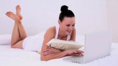 genç çekici bir kadın onu laptop kullanarak onu yatakta yatarken