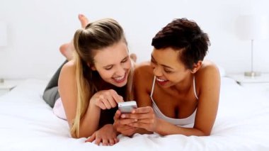iki güzel arkadaş manifatura yatakta yatarken Smartphone