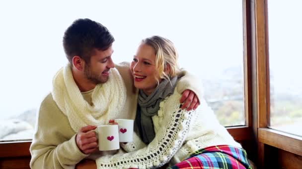 Cute couple cuddling together under a blanket in their ski lodge — Stock Video