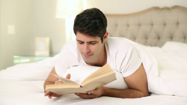 快乐英俊的男人在床上读书 — 图库视频影像