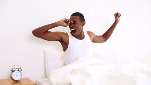 Sonriente hombre bostezando y estirándose sentado en la cama — Vídeos de Stock