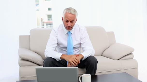 Homem de negócios casual trabalhando no laptop e falando no telefone na mesa — Vídeo de Stock