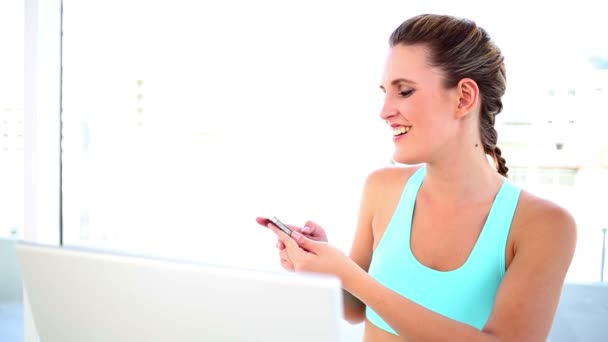 Smiling fit woman sending a text — Stock Video