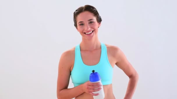 Ajuste morena bebendo de garrafa de esportes e sorrindo — Vídeo de Stock