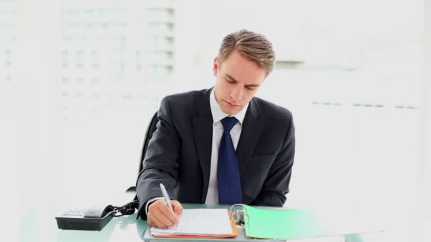 Young annoyed businessman sitting at his desk working — Stock Video