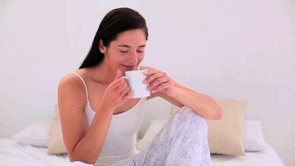 Attraktive Brünette mit ihrem morgendlichen Kaffee im Bett — Stockvideo