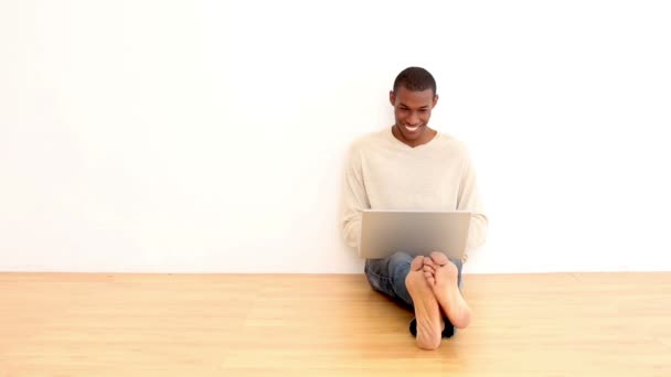 Χαμογελαστός άνθρωπος χρησιμοποιώντας φορητό υπολογιστή που κάθεται στο πάτωμα — Αρχείο Βίντεο